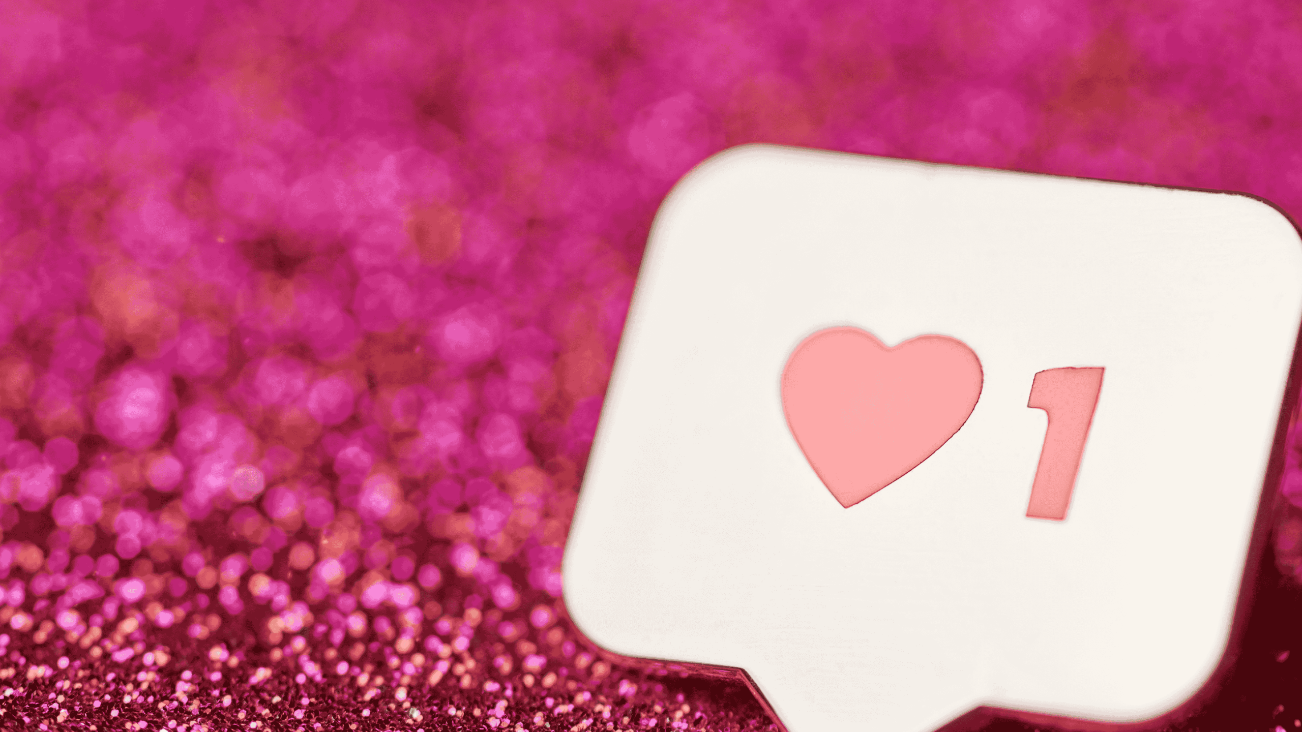 Instagram like notification with a pink heart and the number one, set against a sparkling pink glitter background.