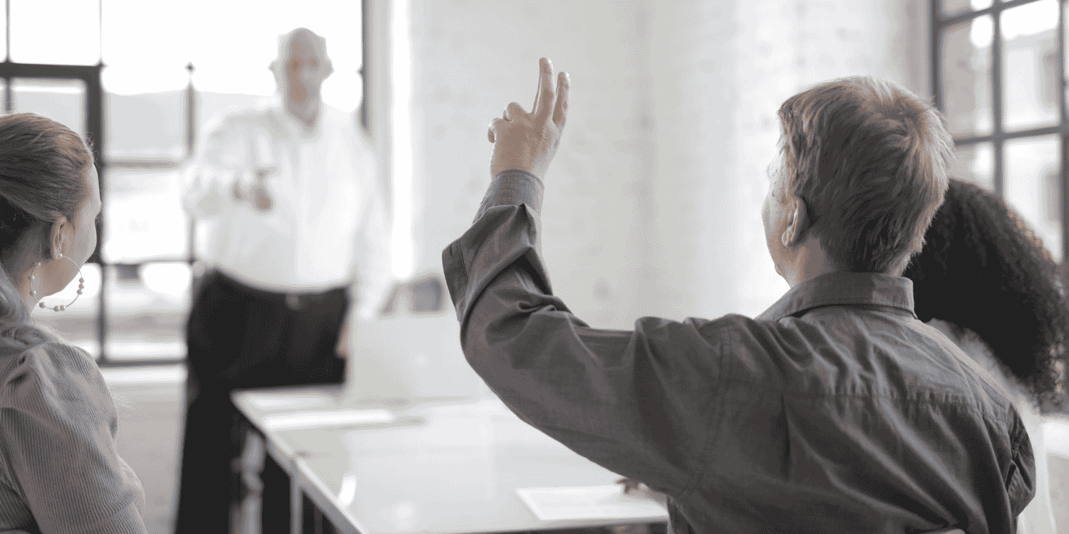 Person raising their hand during a meeting or presentation, indicating a question or request—visual representation of the topic "How to Ask for Giveaways"