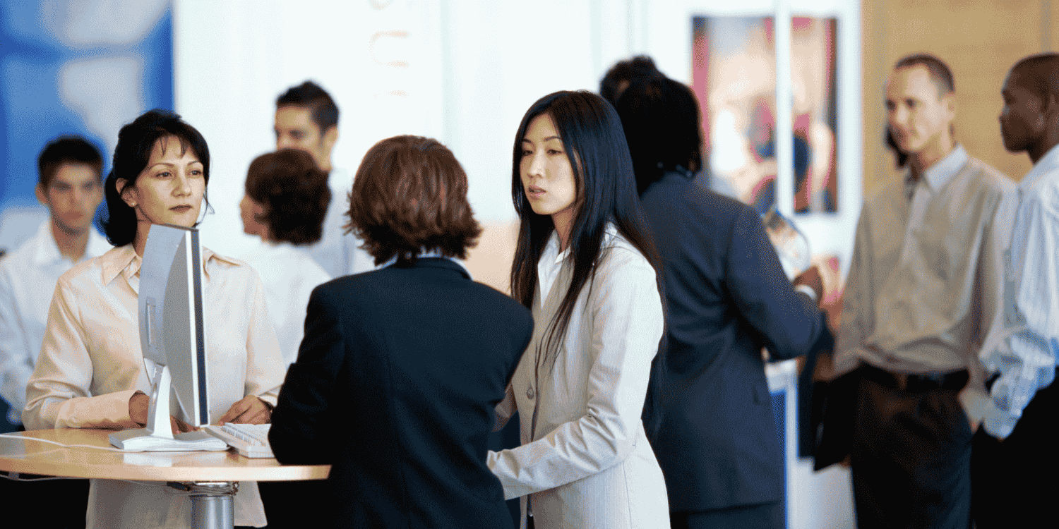 Professionals networking at a trade show booth, highlighting the importance of choosing the best giveaways like branded pens, tote bags, and tech accessories to attract visitors.