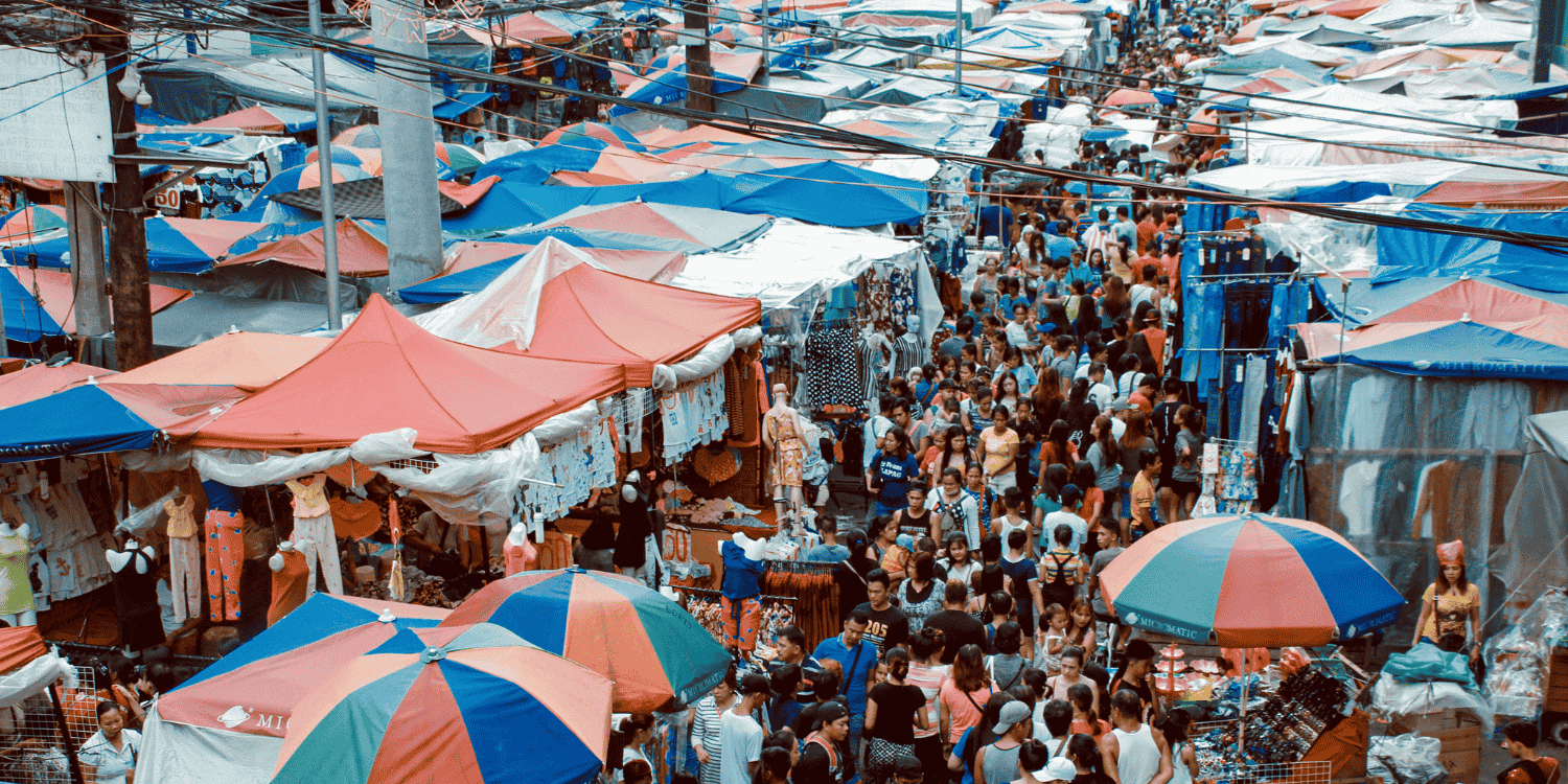 Crowded market scene in Divisoria, Manila showing stalls with clothes and accessories under colorful tents—ideal spot to buy birthday giveaways in bulk.